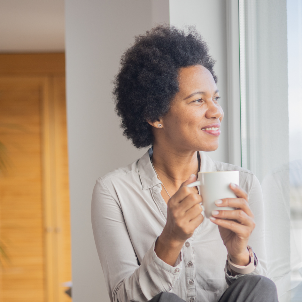 Mixed race woman sat on window ledge looking satisfied