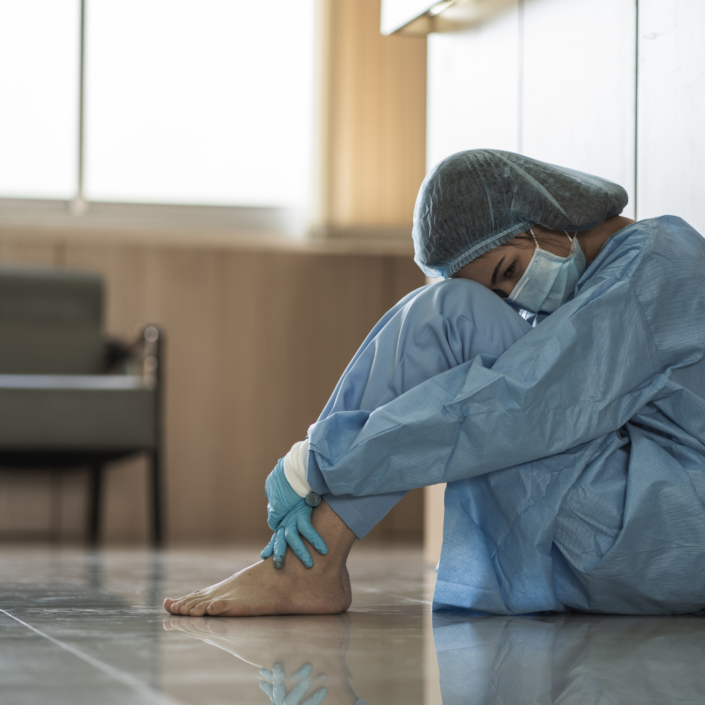 Asian Female Doctor Wearing Surgical Mask Sitting on Floor Tired and Depressed from Work